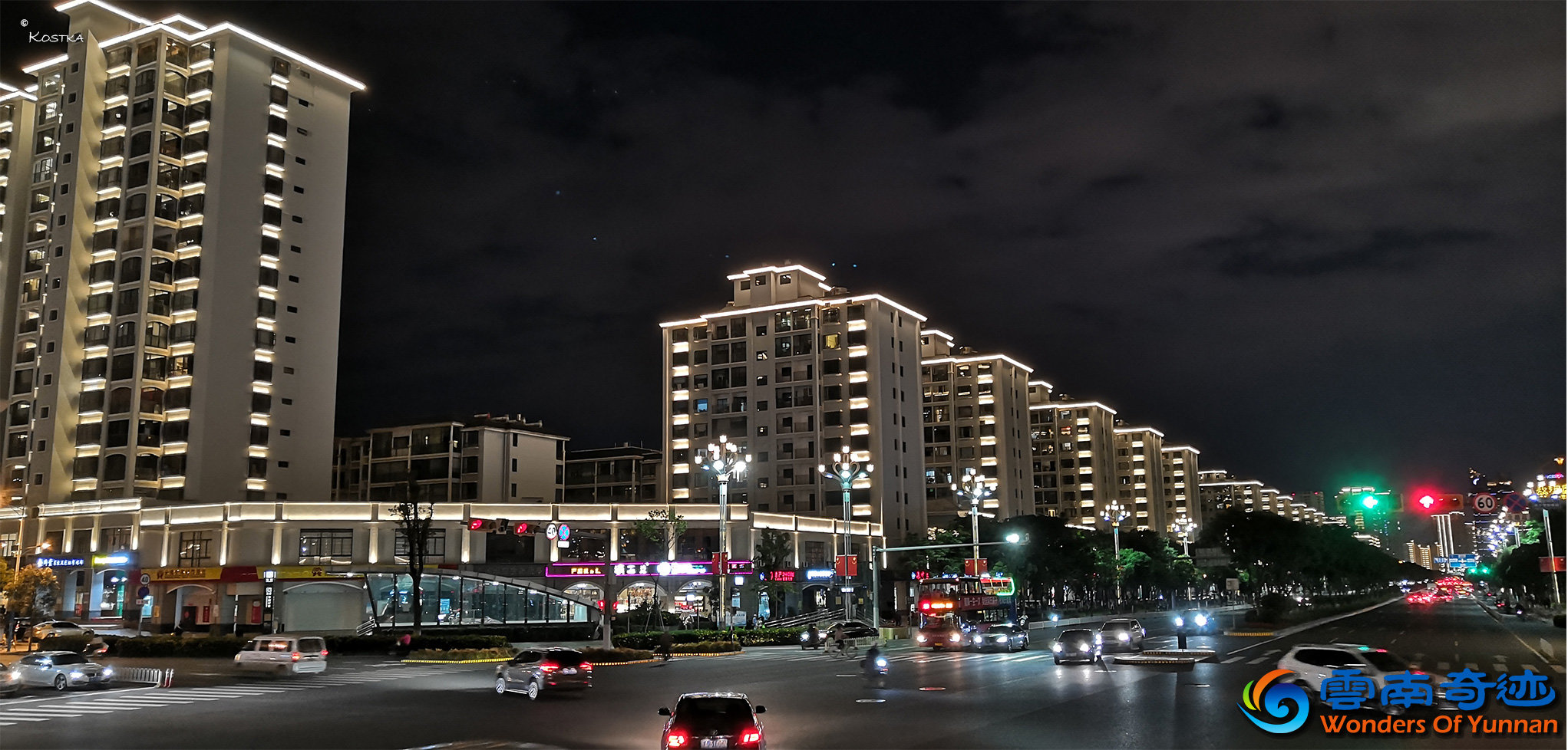 View over junction of Beijing road (北京路) and Gufeng Road (谷丰路) at 羊肠村 station with colored lights houses in the background at night 