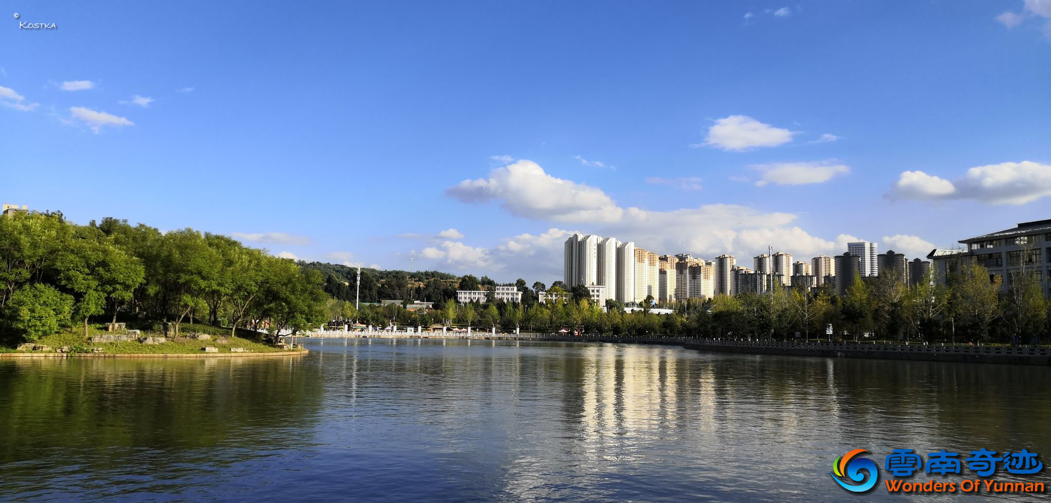 View over the upper lake of Waterfall Park on a sunny day in late October with people enjoying the trees, plants and flowers